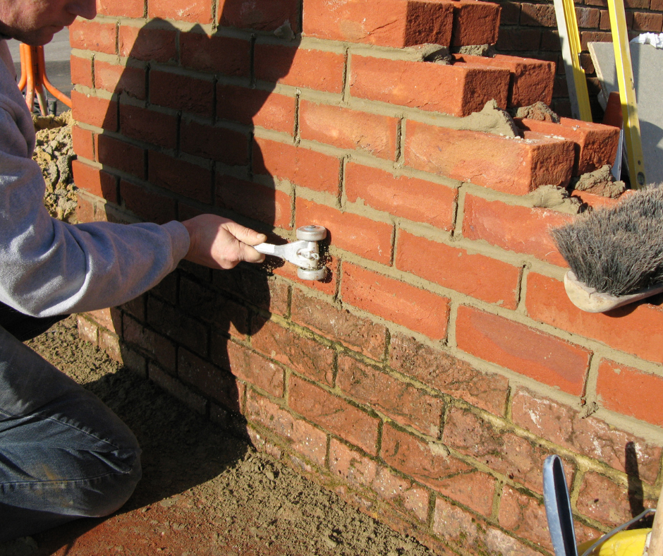 A man is working on a brick wall with a tool