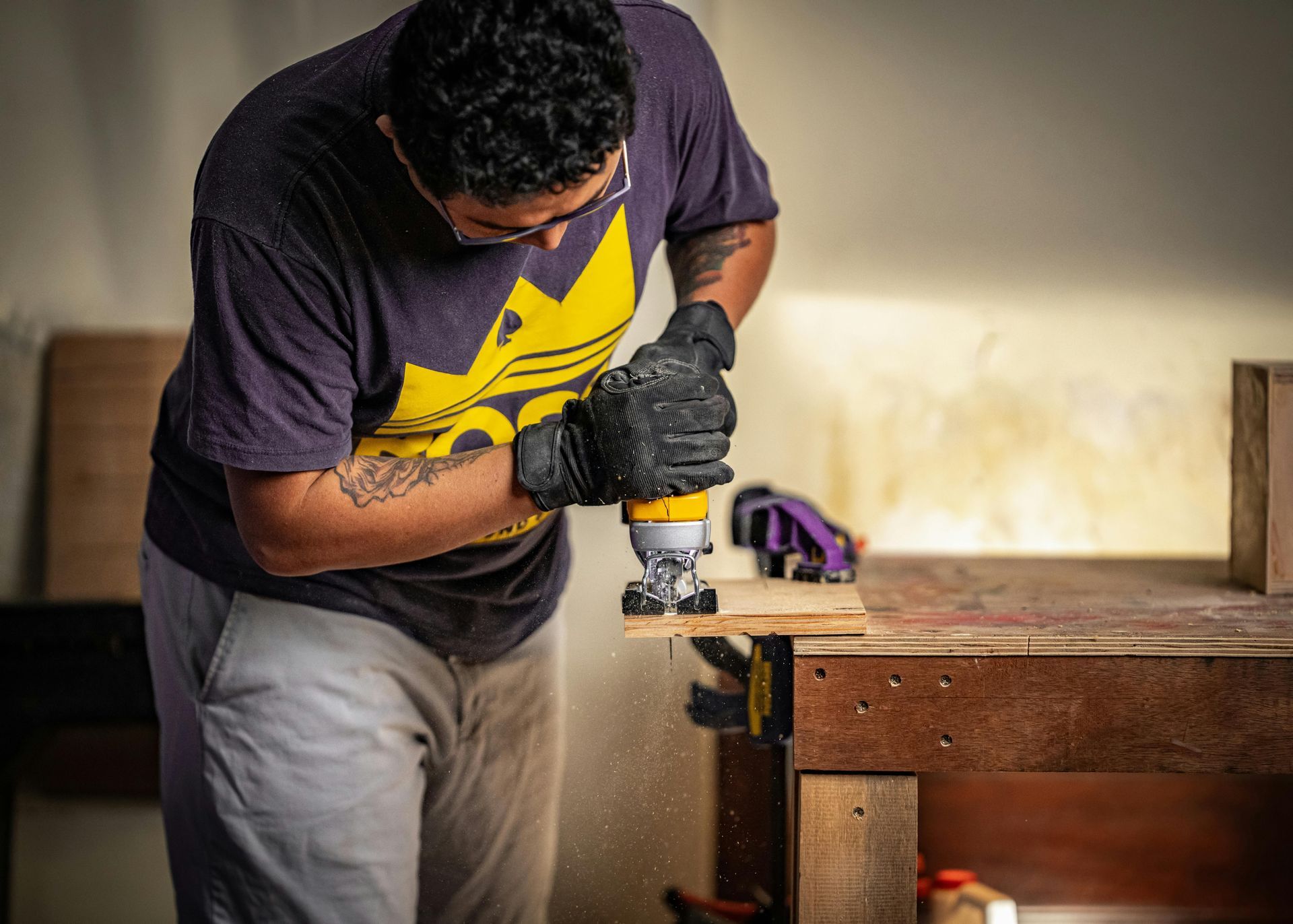 A man is using a jigsaw to cut a piece of wood.