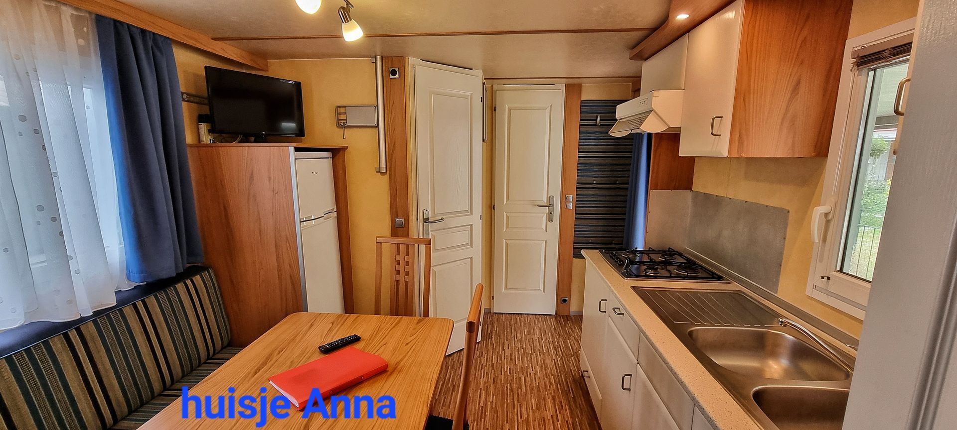 Chalet Anna met keuken en eethoek. Lichte houten kasten, spoelbak en fornuis.