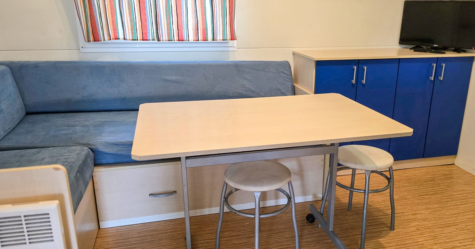 Interieur van de woonkamer met een blauwe bank, tafel en blauwe kasten.