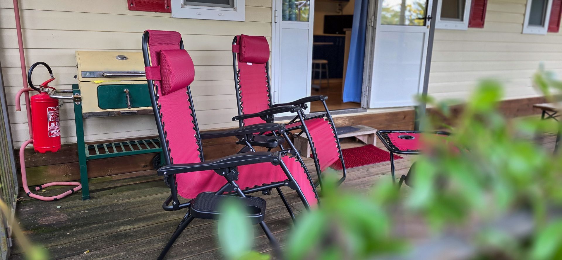 Twee rode ligstoelen op een veranda.