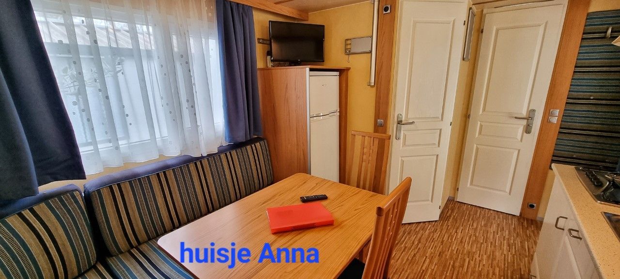 Interieur chalet Anna . Er is een raam, een zithoek, een tafel, een televisie.