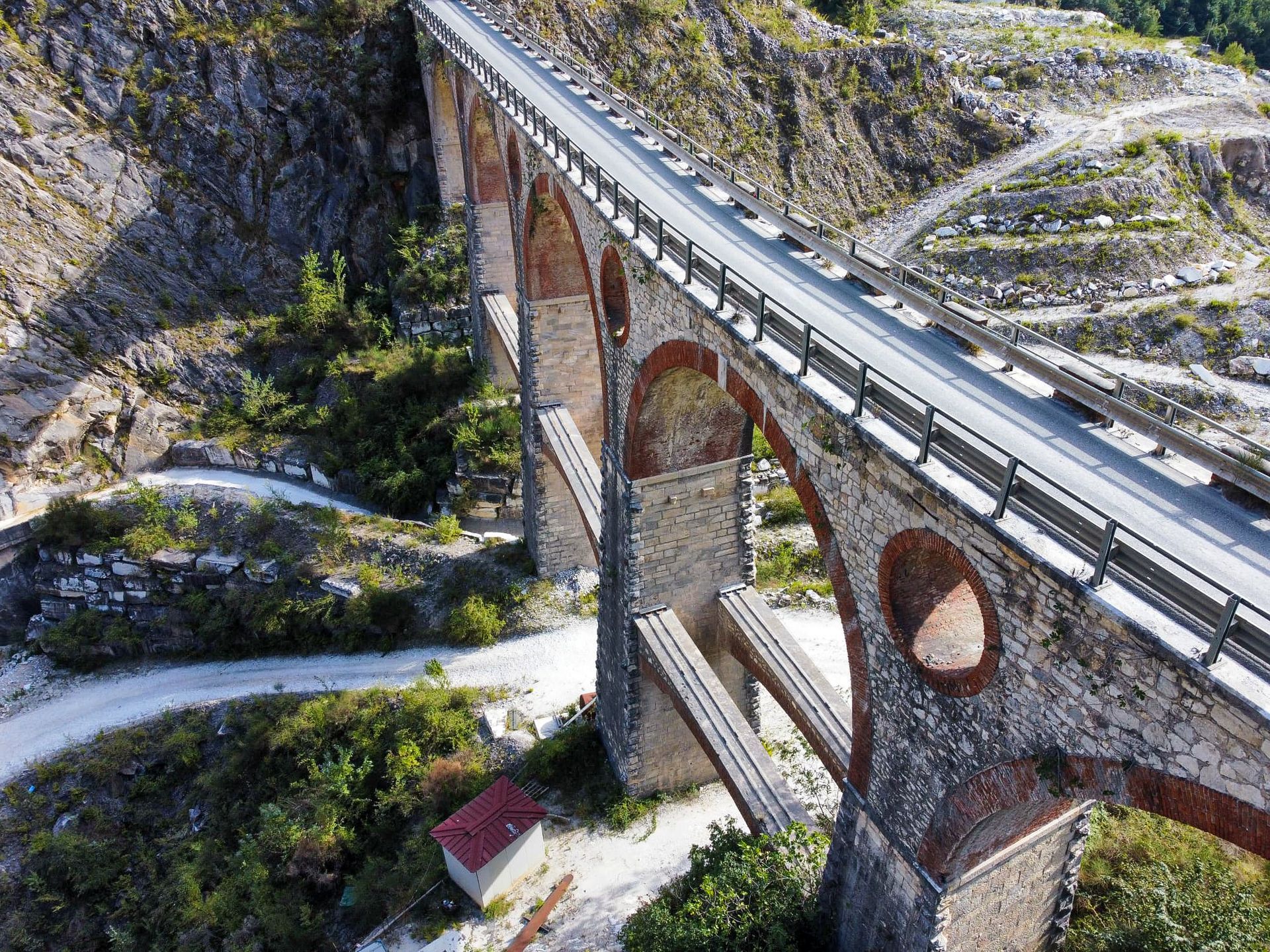 Stenen boogbrug over een vallei, met een weg erbovenop. Marmergroeven Carrara