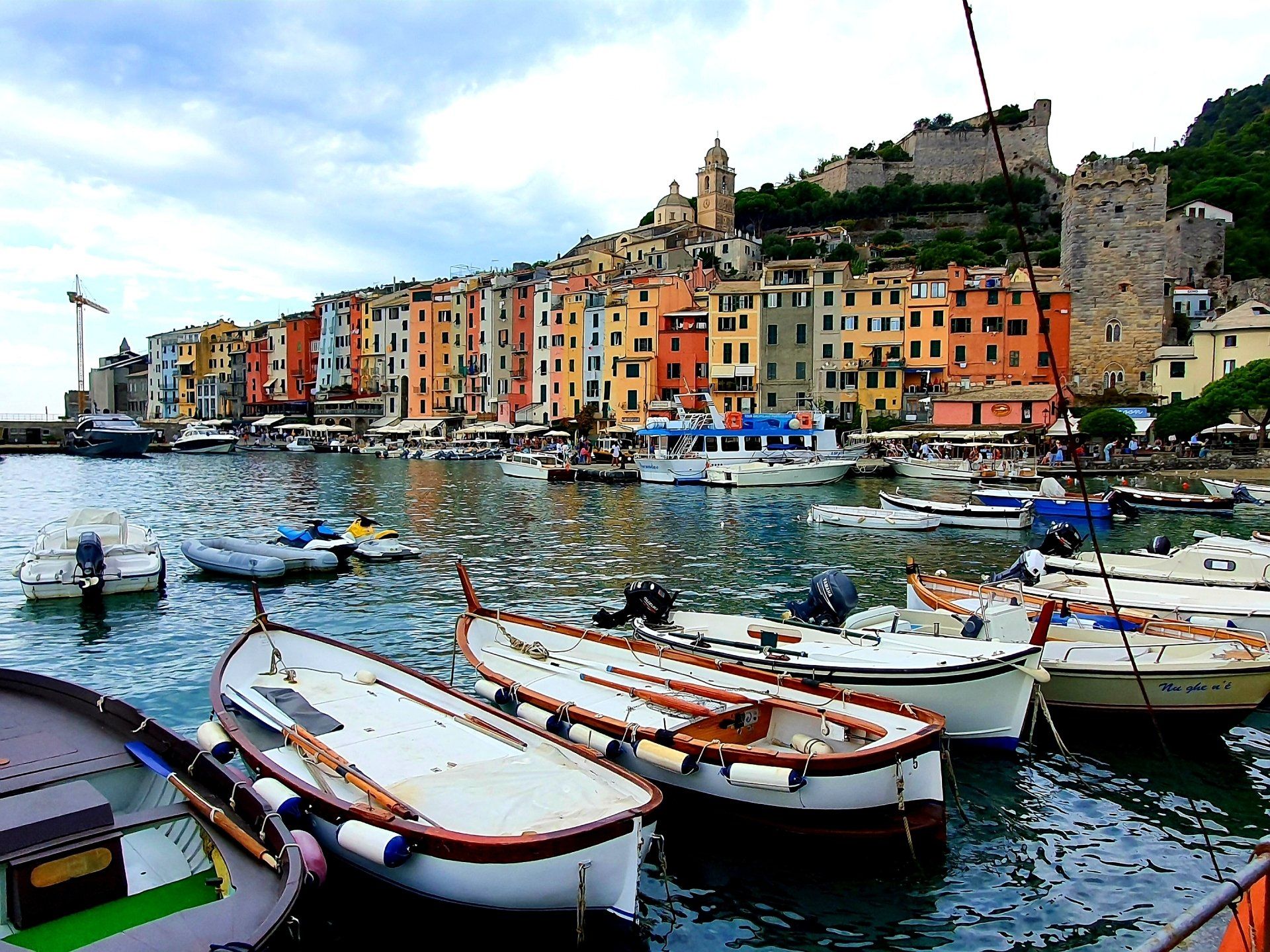 Boten aangemeerd in de haven, kleurrijke gebouwen langs de kust, kasteel op een heuvel in Portovenere, Italië.