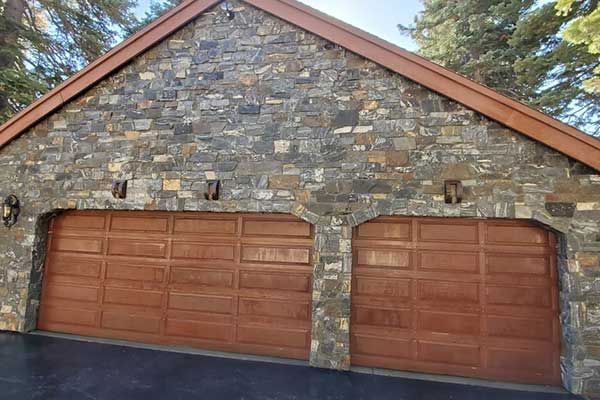 A large stone garage with two wooden garage doors