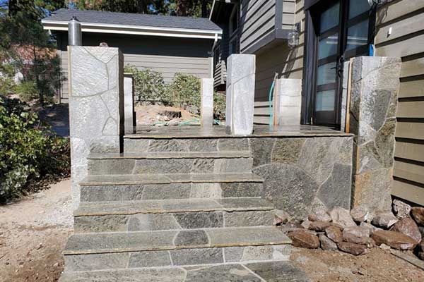 A stone porch with stairs leading up to a house.