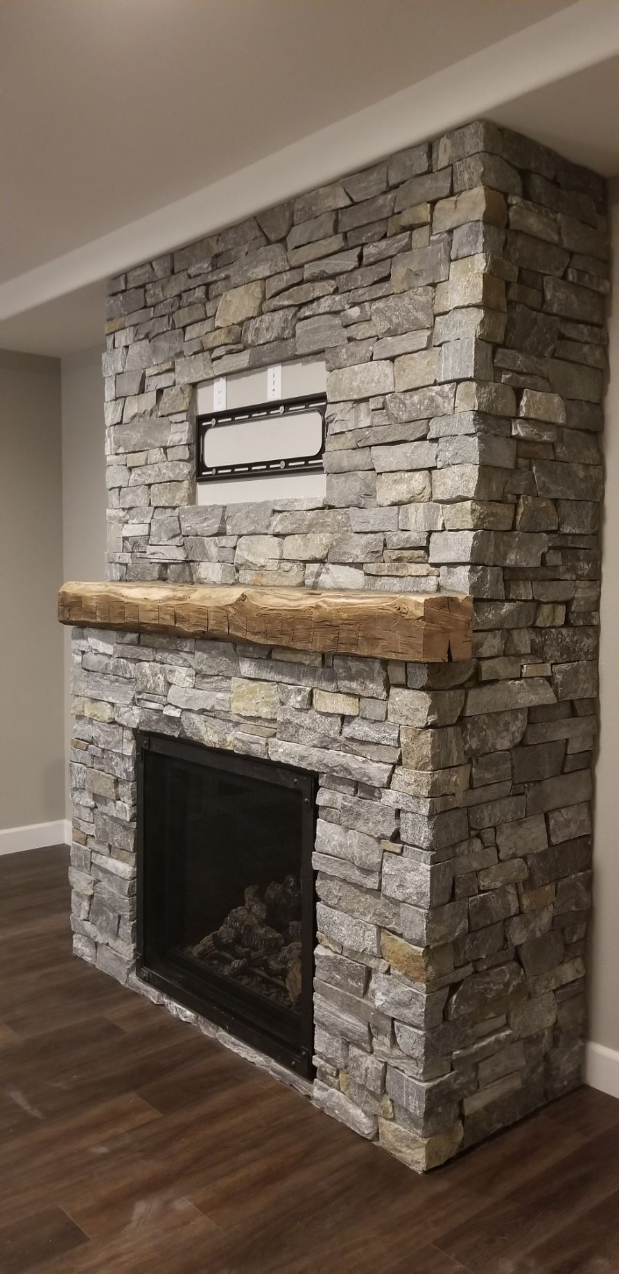 A stone fireplace with a wooden mantle in a living room