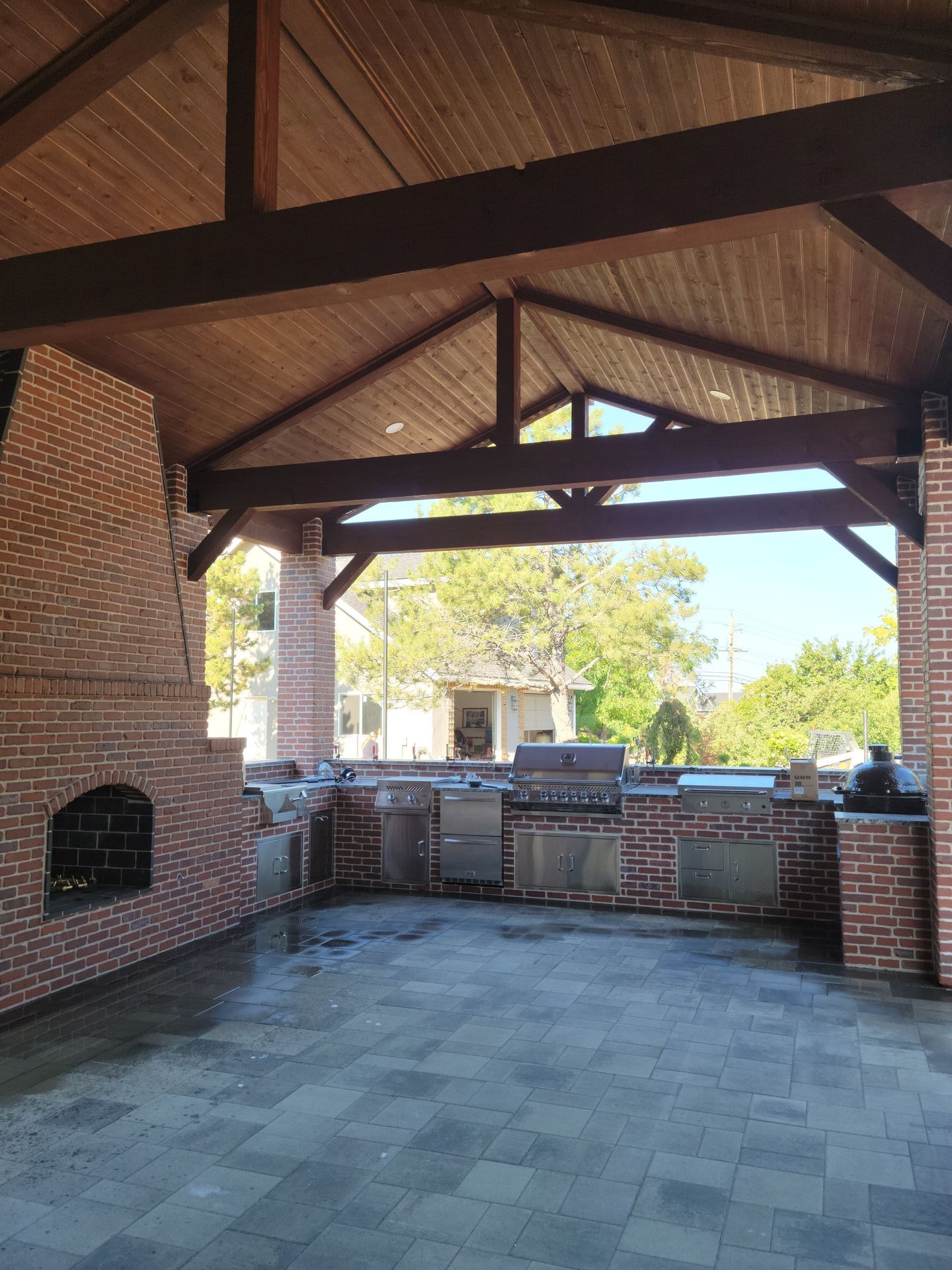 An outdoor kitchen with a wooden ceiling and brick walls