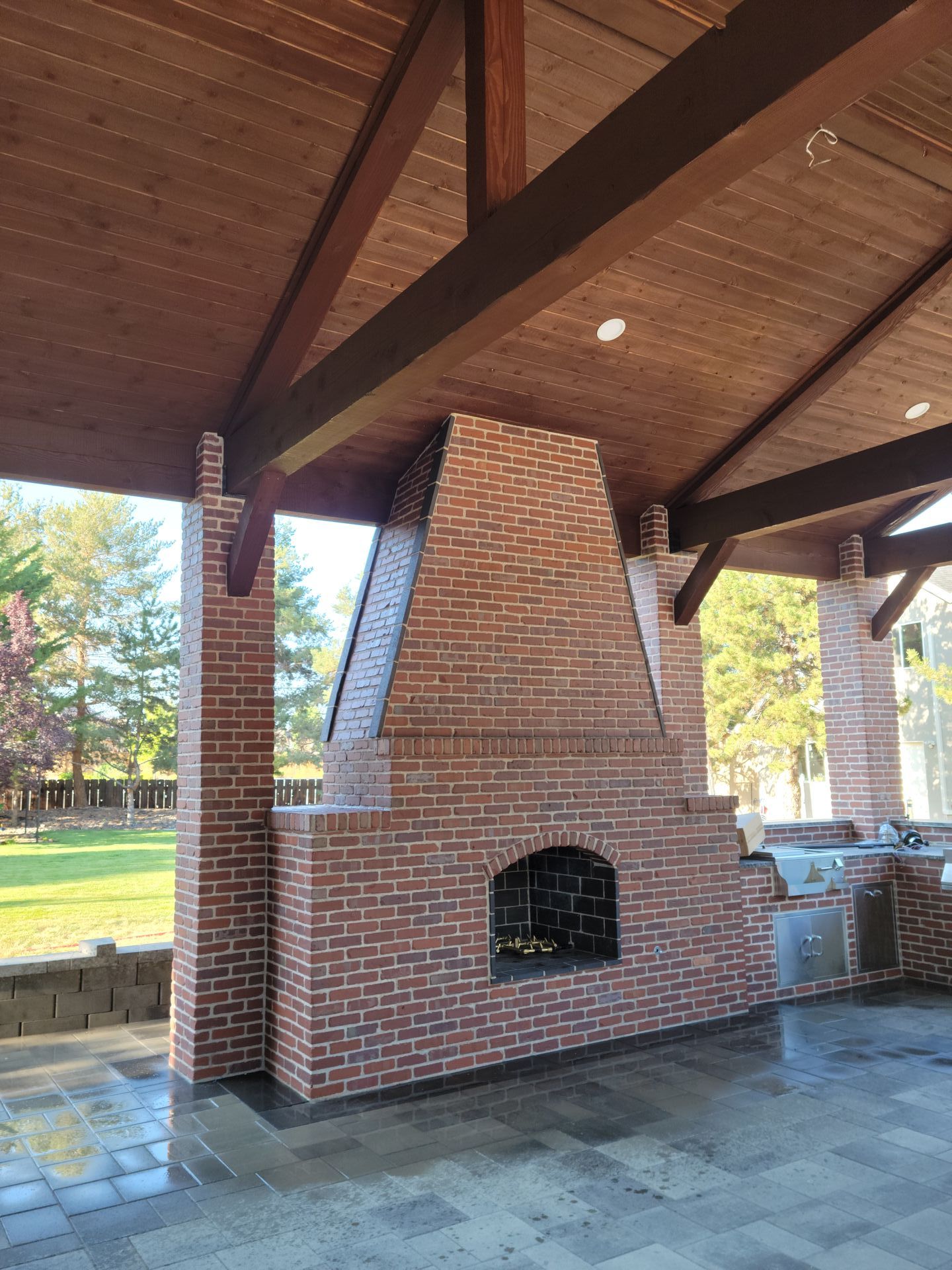 A large brick fireplace is under a wooden roof