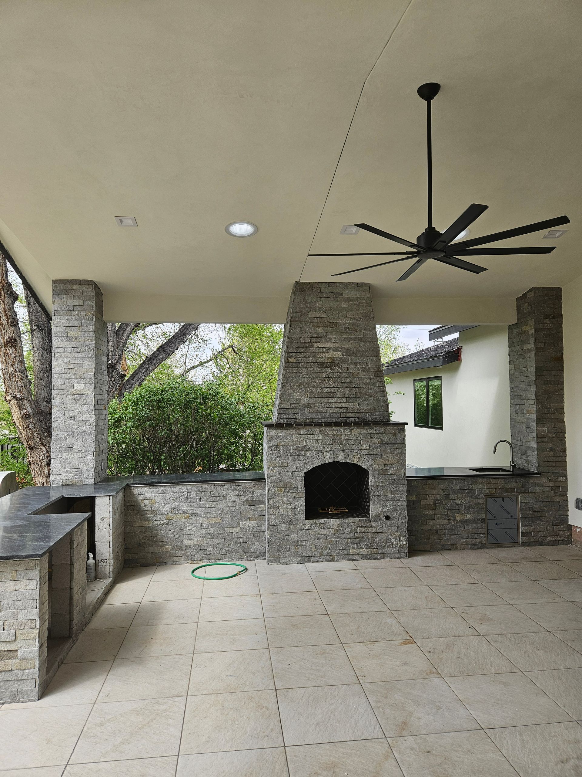 A patio with a fireplace and a ceiling fan
