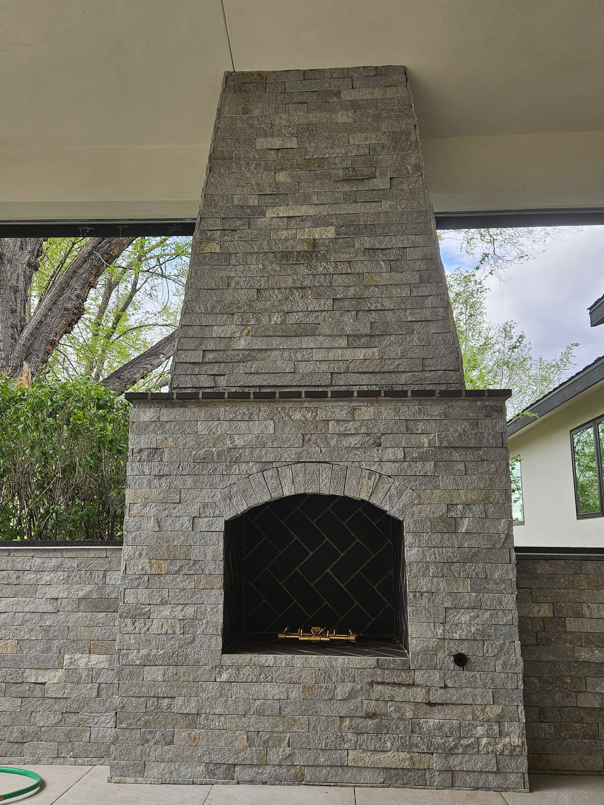 A large brick fireplace with a hose next to it