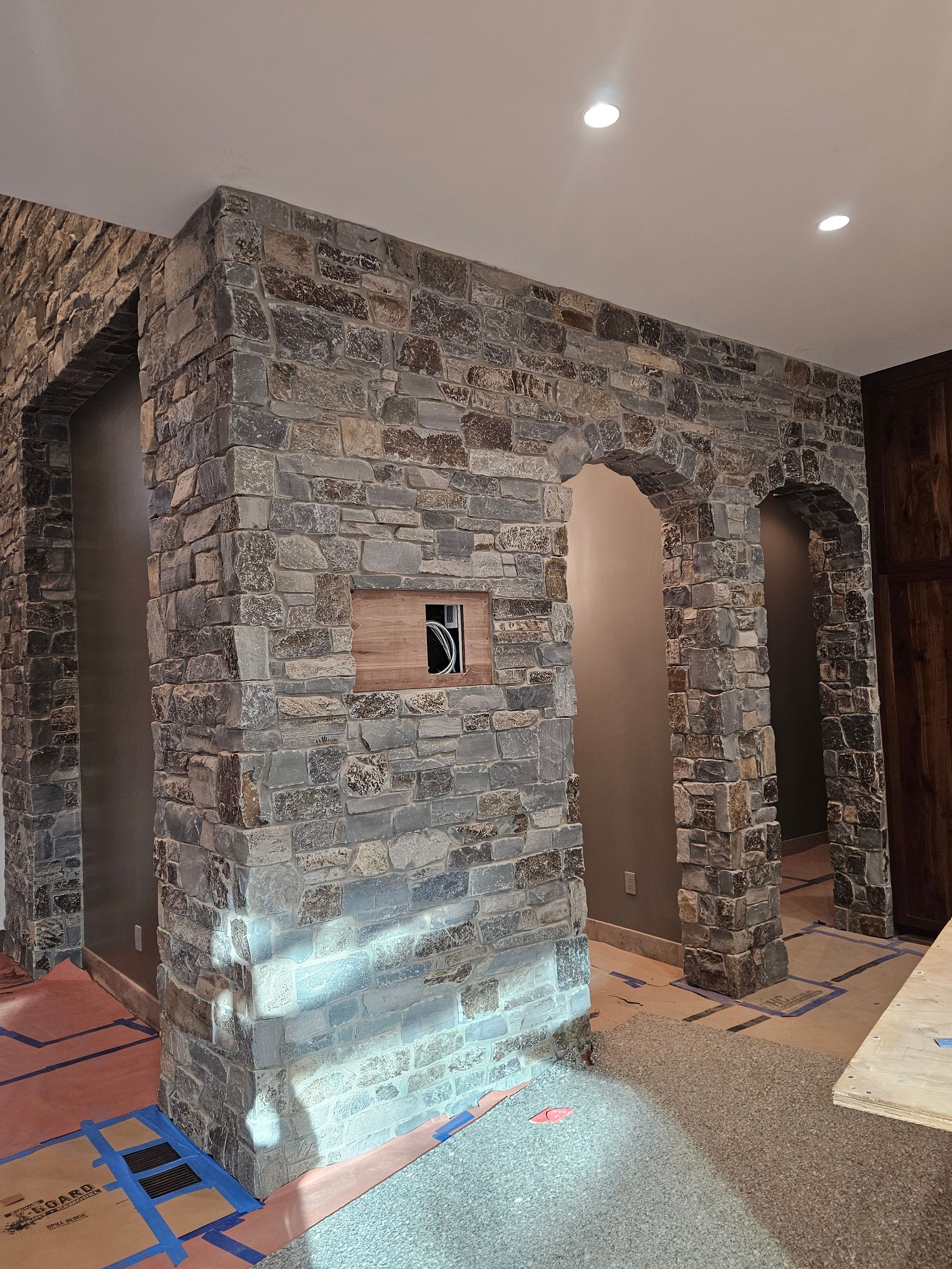 A room with a stone wall and arches in it