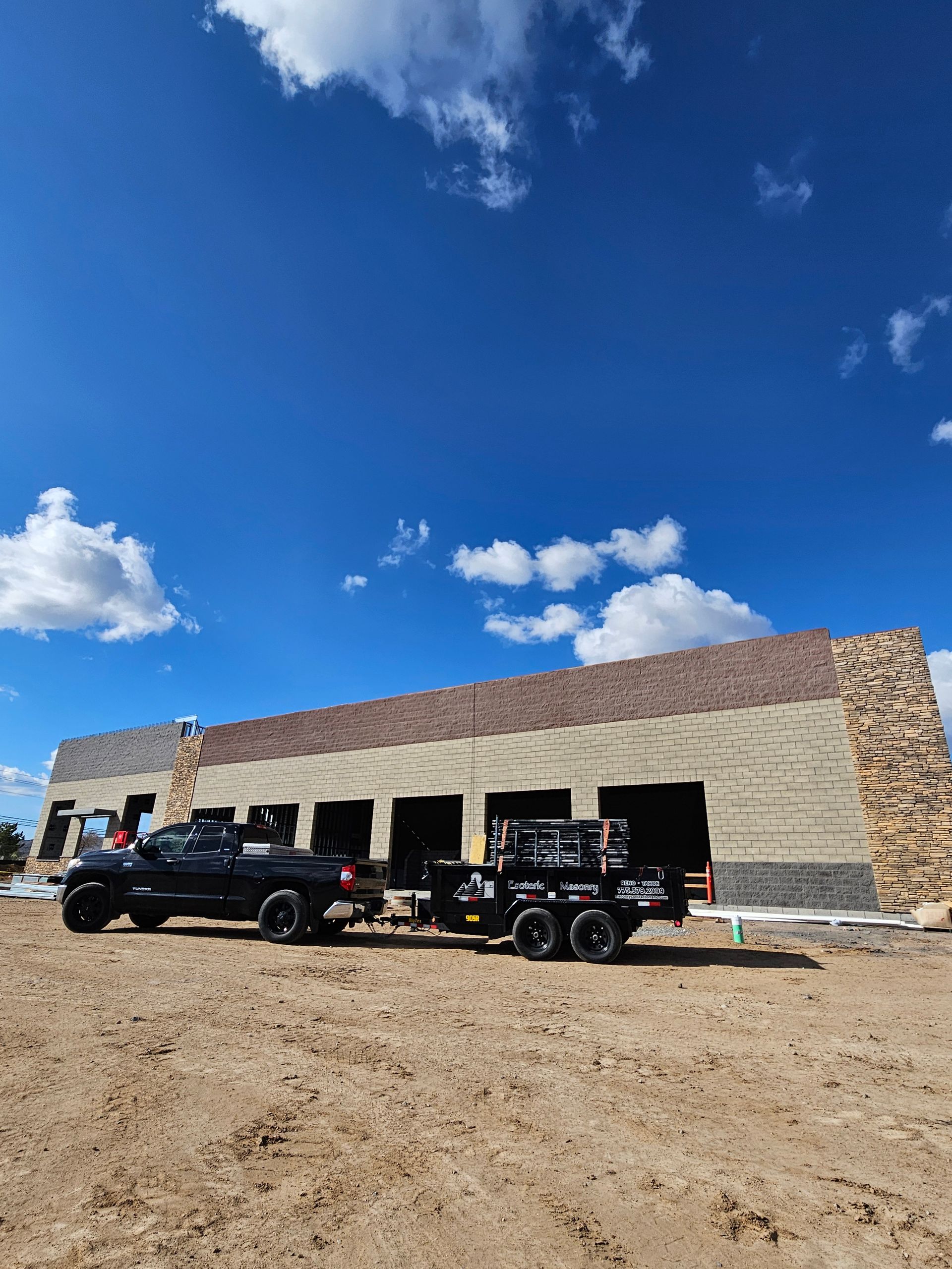 Two trucks are parked in front of a building under construction