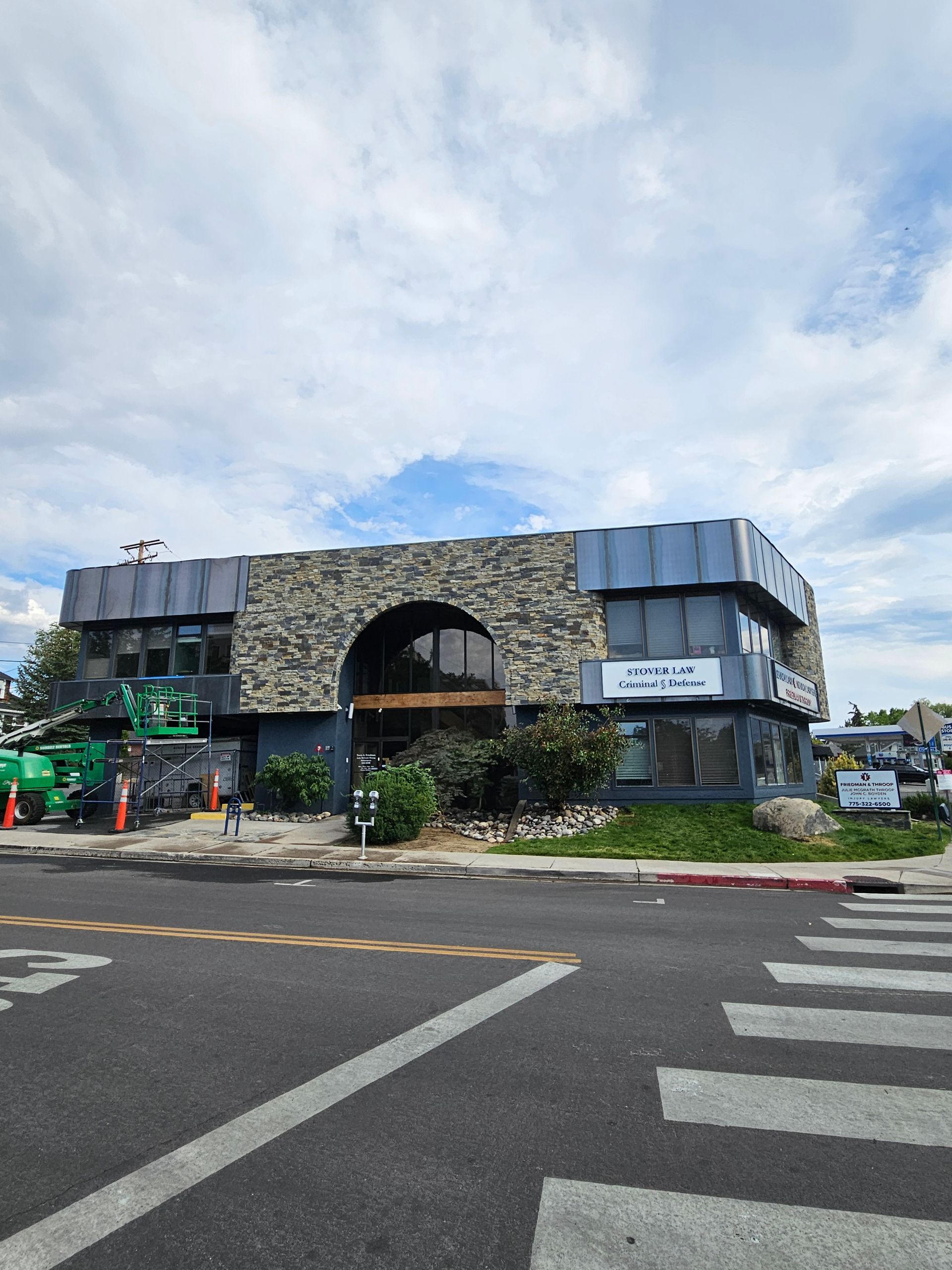 A large building with a stone facade is sitting on the corner of a street