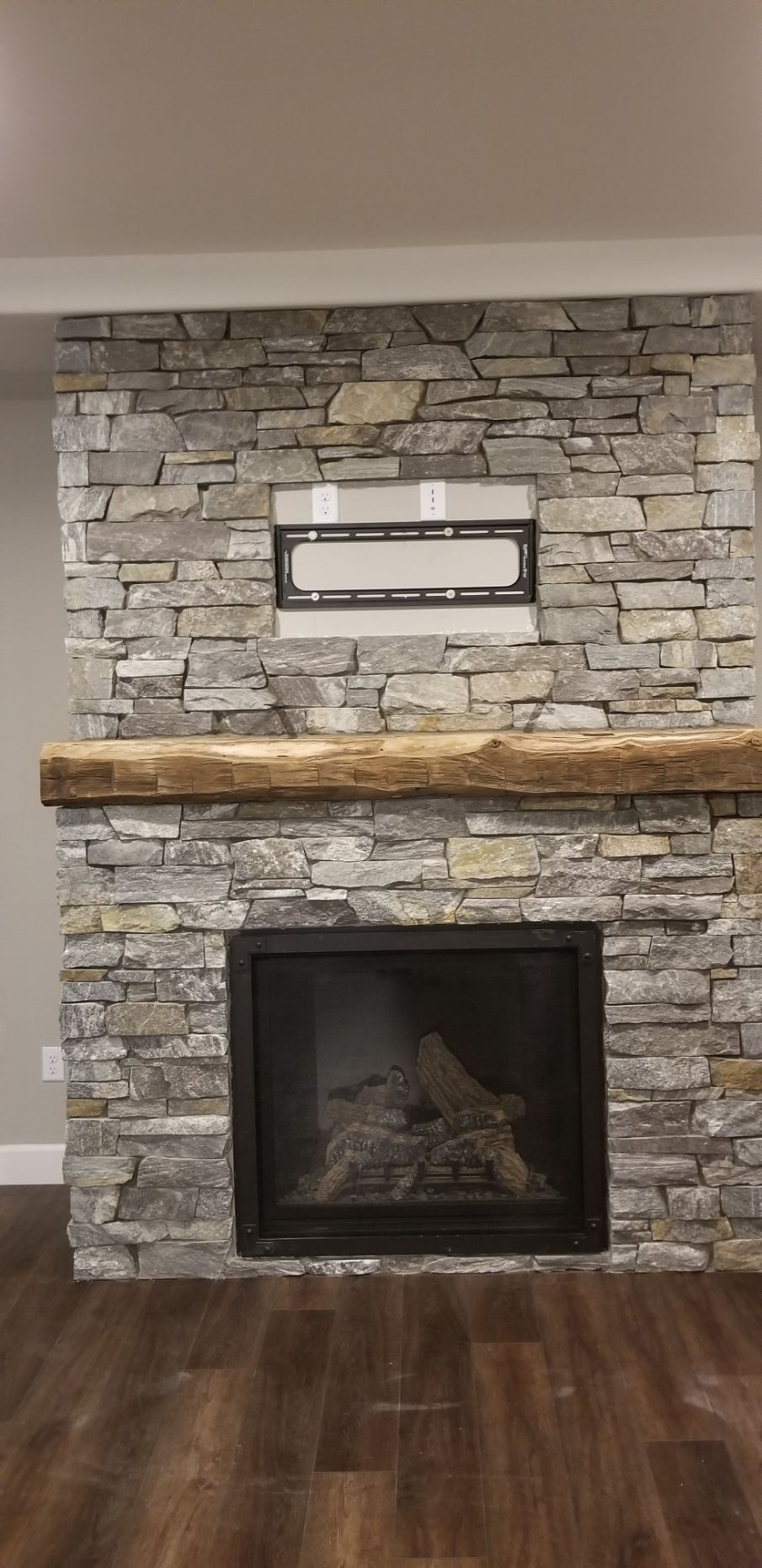 A fireplace with a stone wall and a wooden mantle in a living room