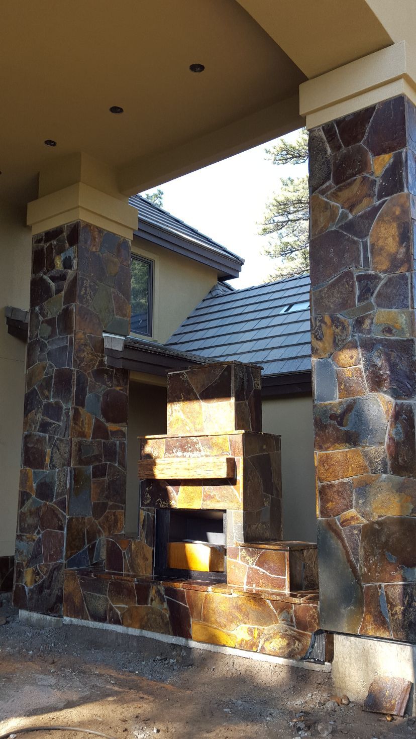 A stone fireplace is built into the side of a house