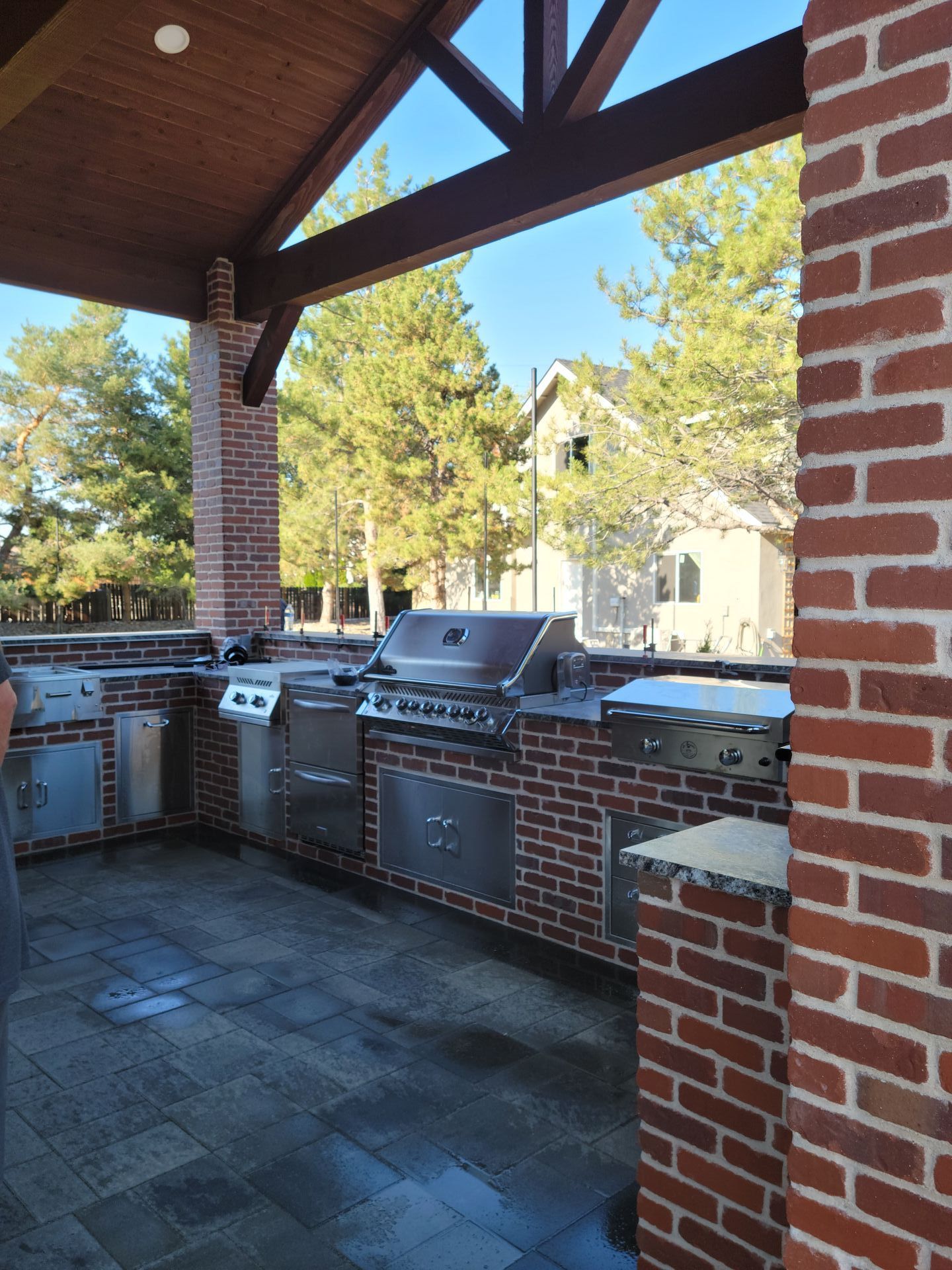 An outdoor kitchen with a brick wall and a grill