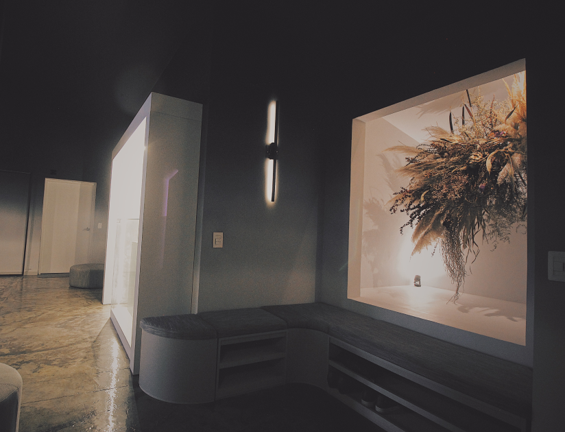Interior moderno con un banco incorporado, arreglo floral seco en un nicho iluminado y un elegante aplique de pared.