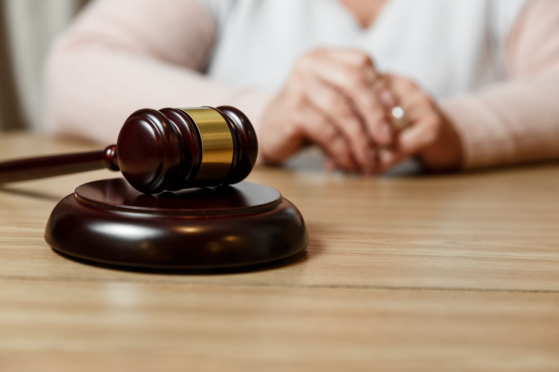 Judge’s gavel on a wooden desk with a blurred person in the background
