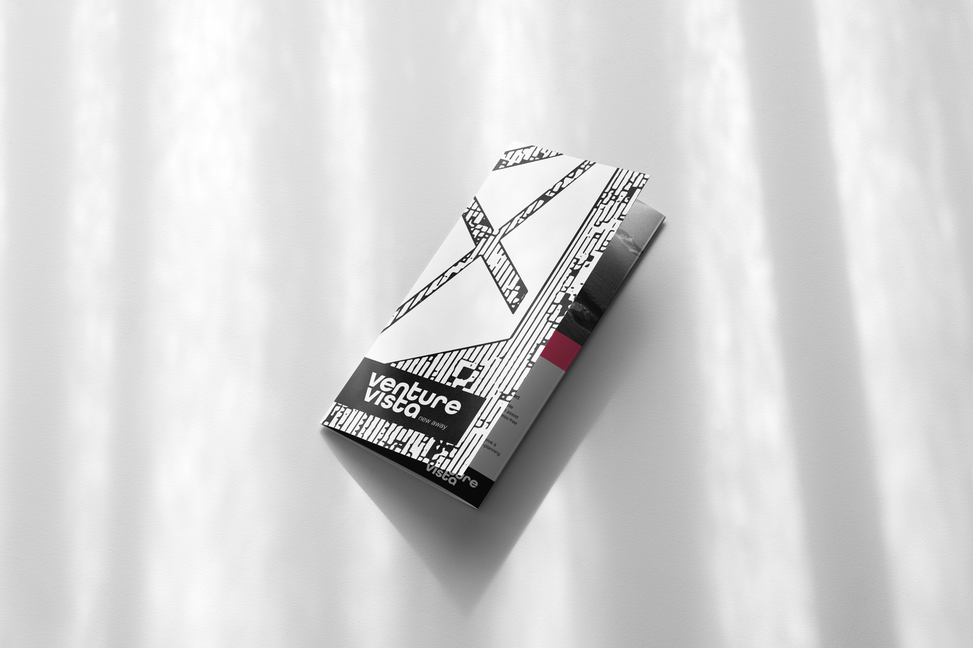 Brochure with black and white design and a red accent, casting shadows on a white surface.