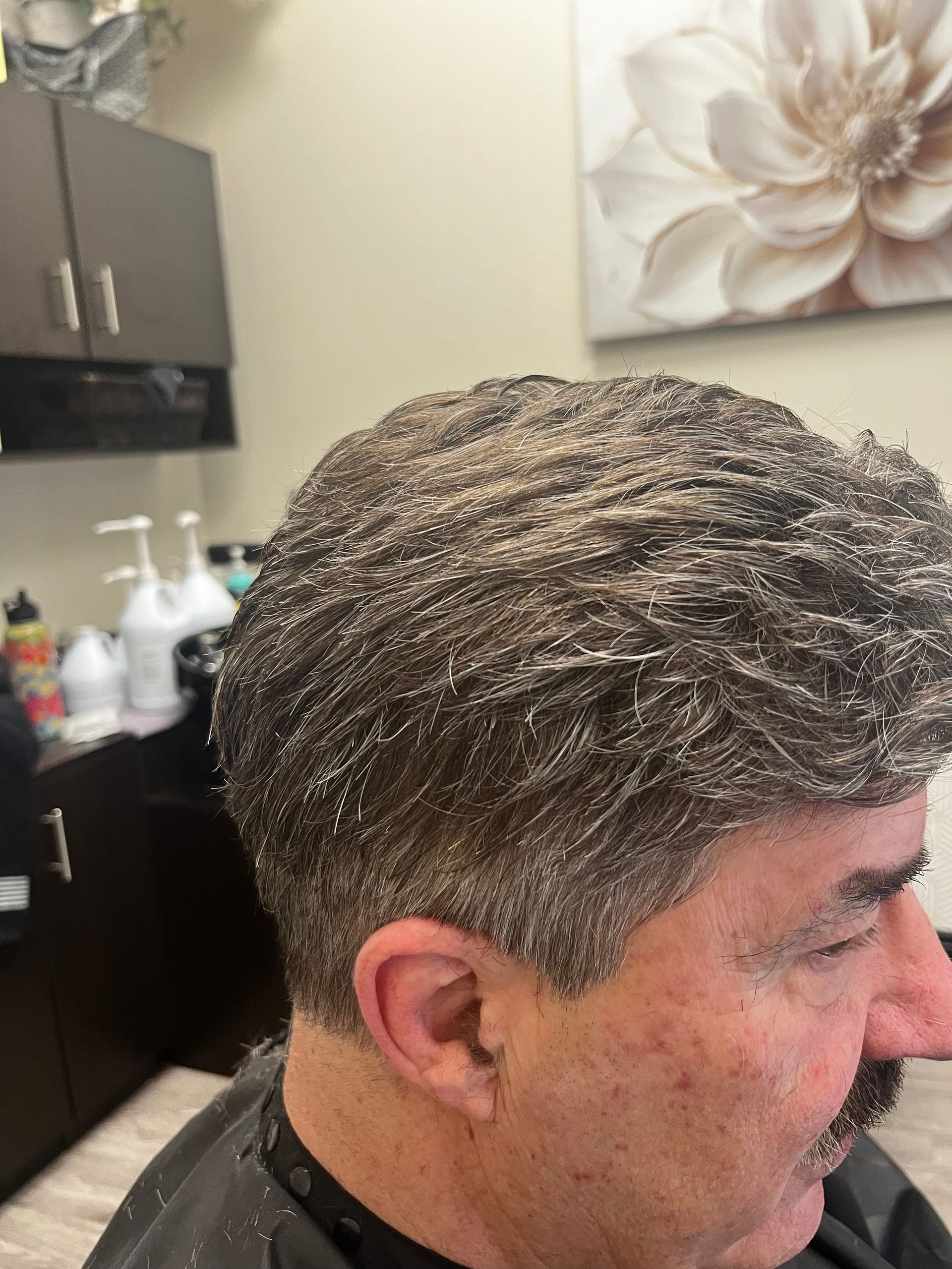 A salon customer sits in a chair with white hair styling product applied throughout their brown hair.