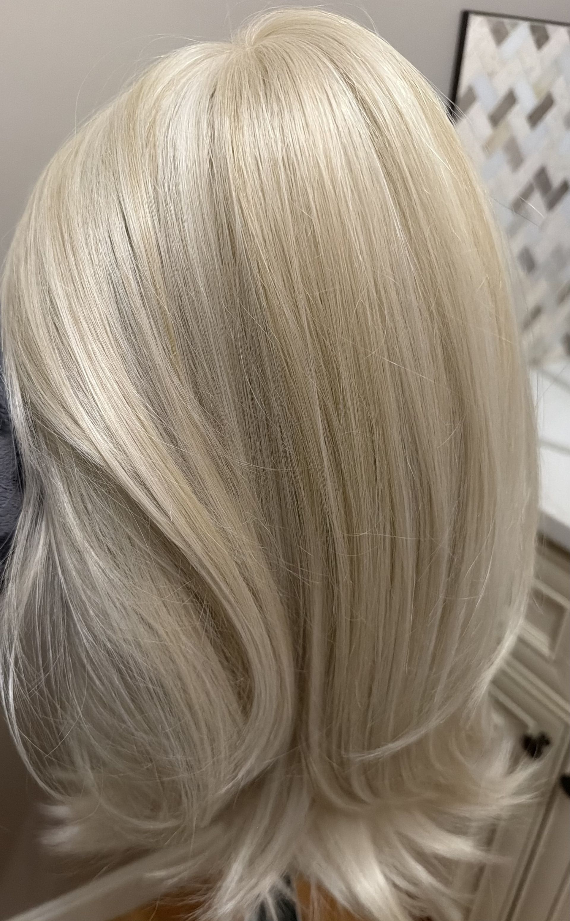 Hands attaching a hair topper with a clip to a person's head, adding volume to brown hair.