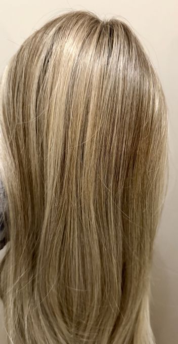 Person cutting hair, using a comb and scissors on blonde hair.