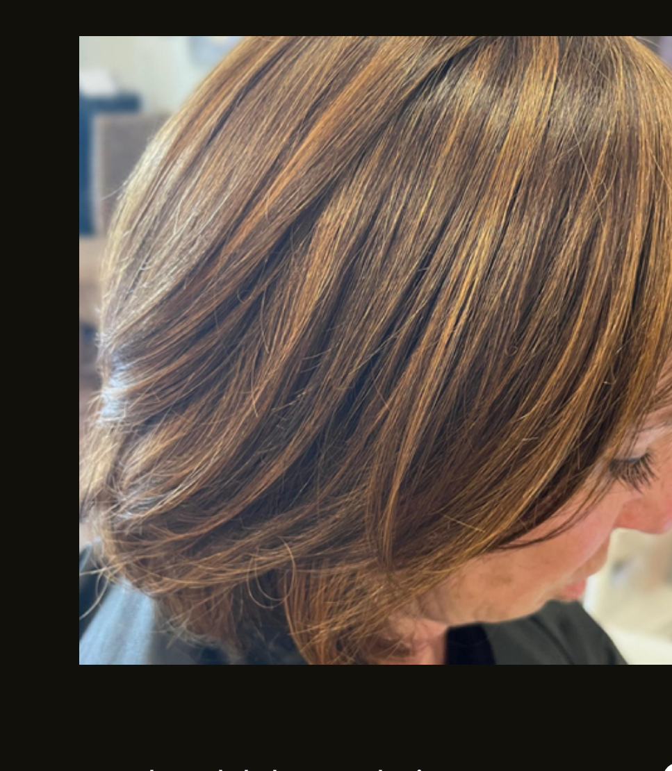 Close-up of shoulder-length, layered brown hair with caramel-toned highlights styled in a soft wave.