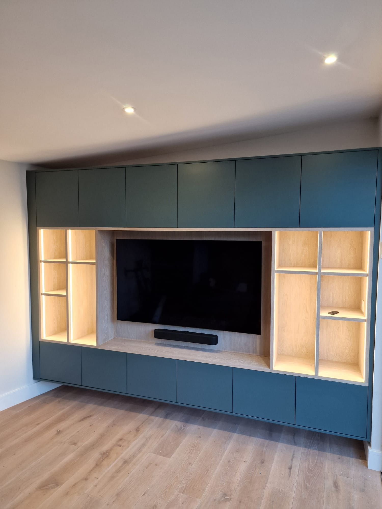 A living room with a large flat screen tv and shelves.