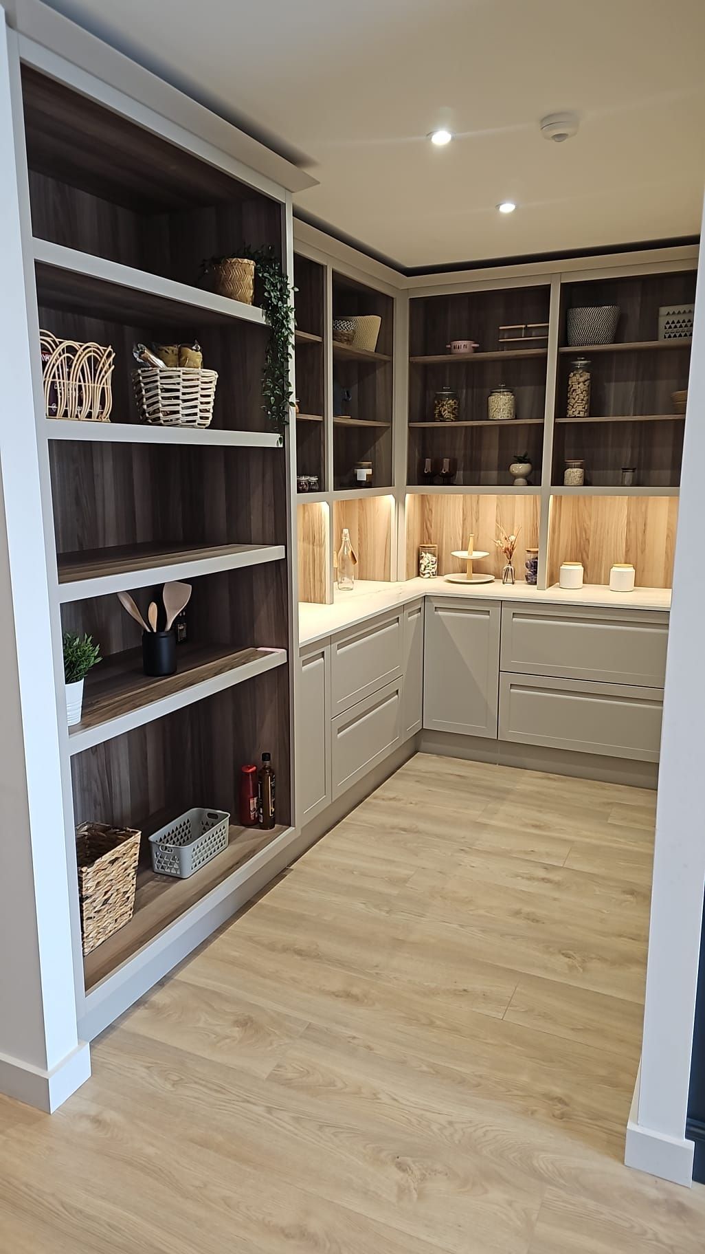 A kitchen with lots of shelves and cabinets and a wooden floor.