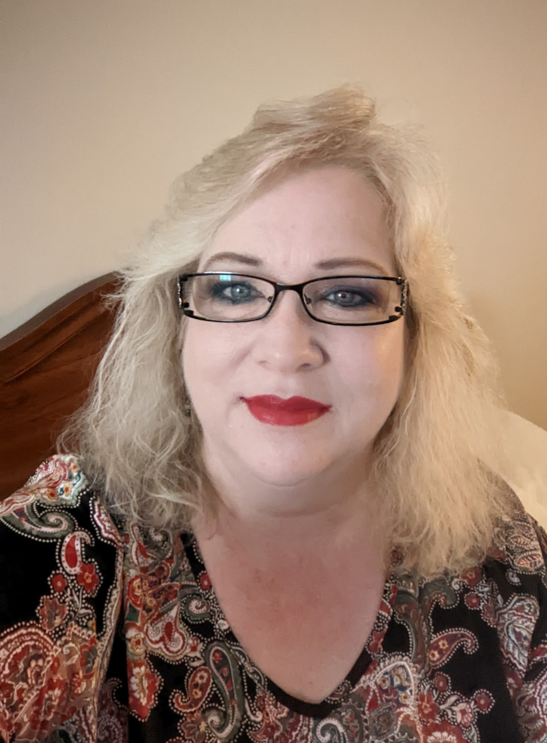 Woman in a white shirt smiling in front of a backdrop with the