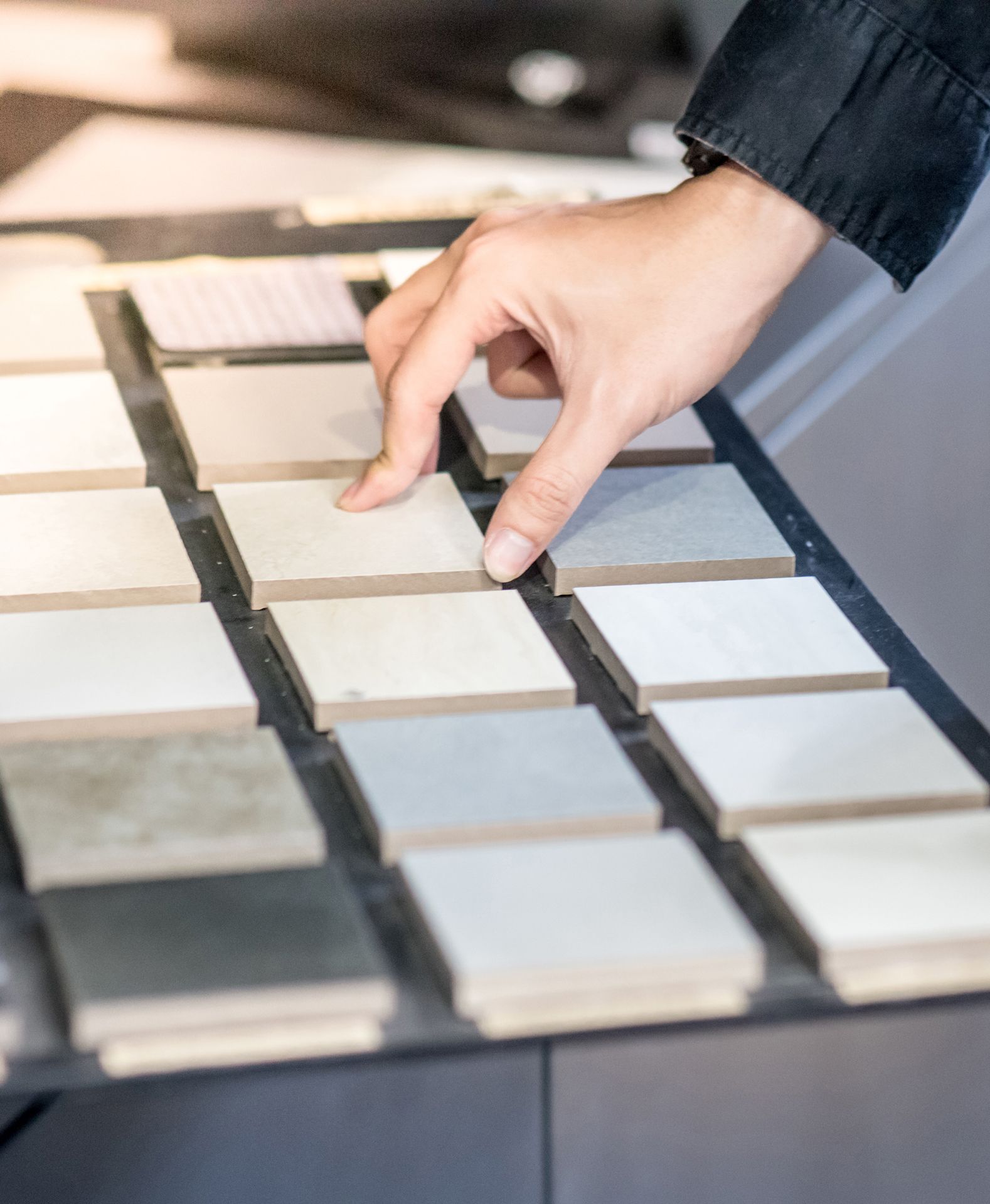 A person is picking a tile from a display of tiles.