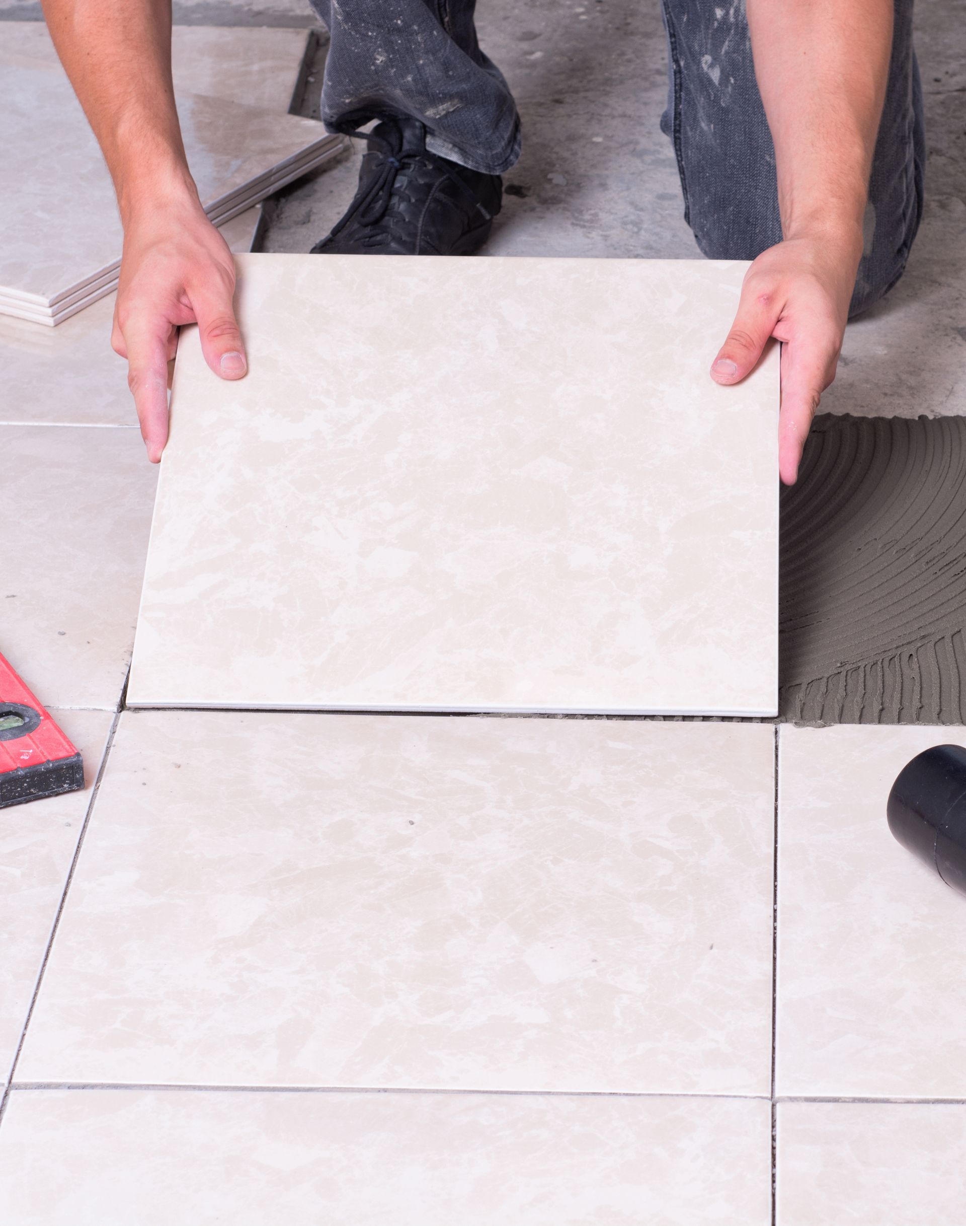 A man is laying a tile on the floor