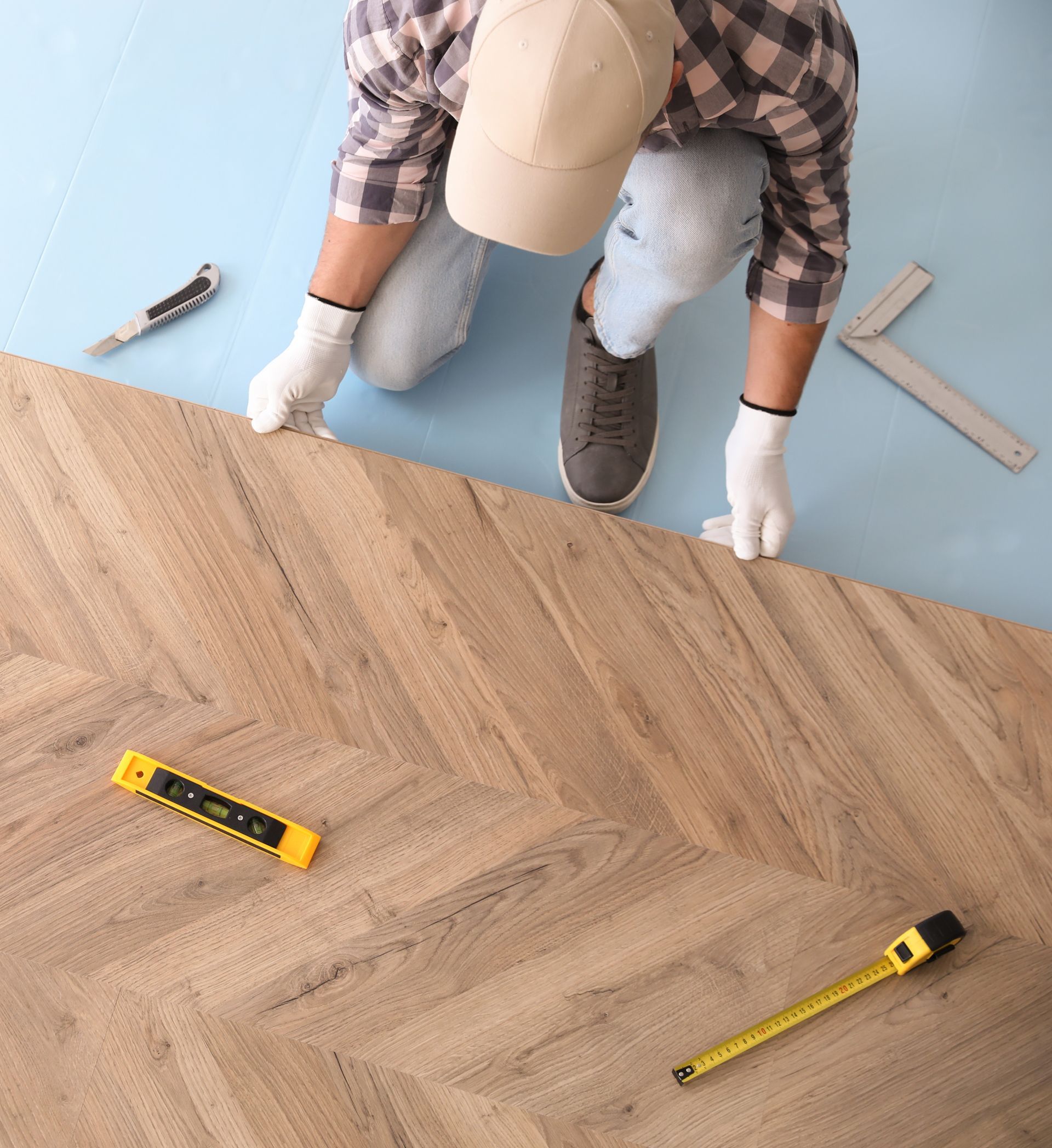 A man is measuring a wooden floor with a tape measure.