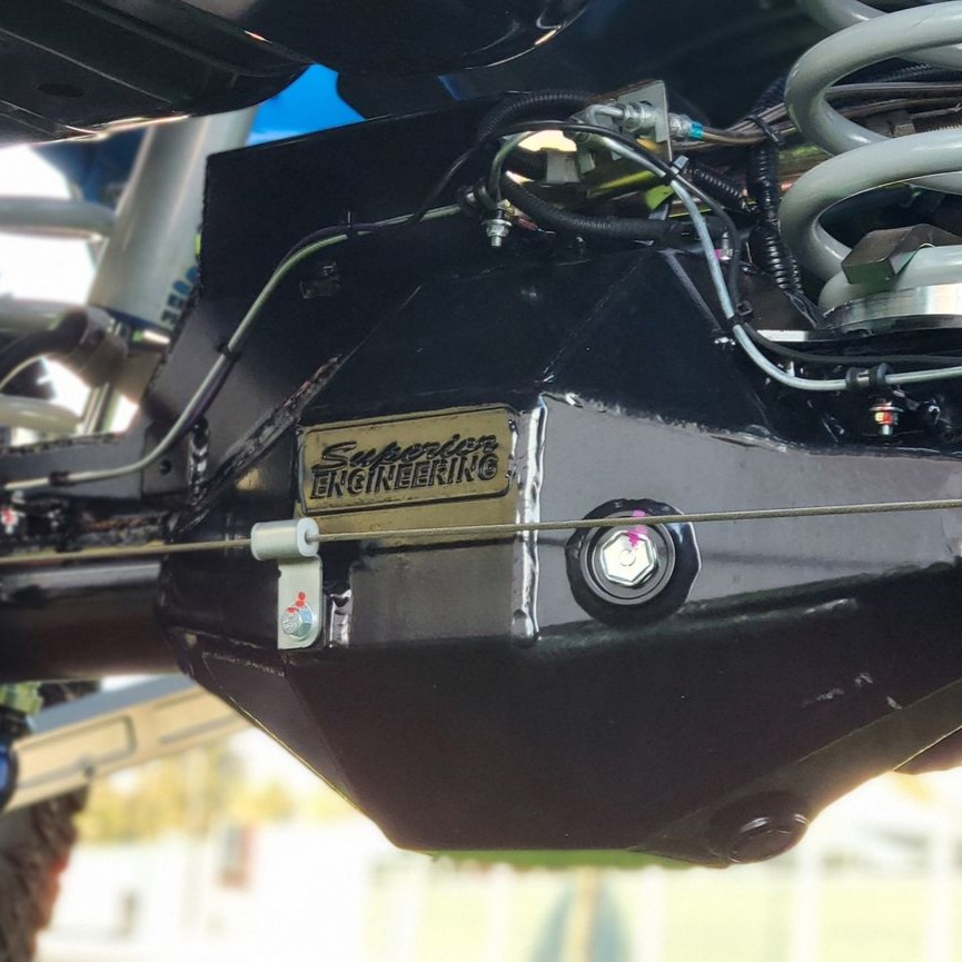 A close-up of a disassembled car differential, showing gears, with a green tool inserted and wiring.