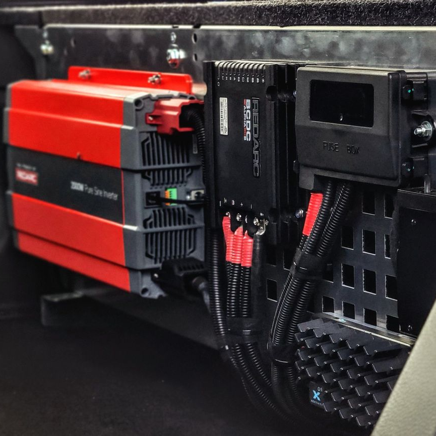 Close-up of a car engine compartment with wires and a black control module installed.