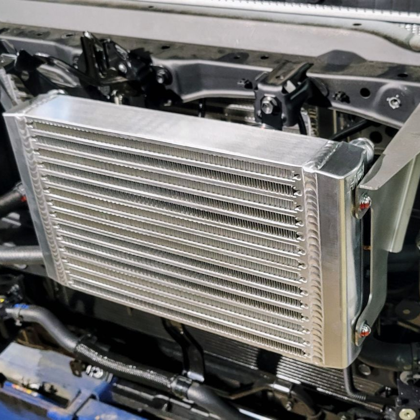 Close-up of a car engine compartment with wires and a black control module installed.