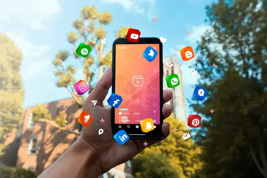 Hand holding a cell phone with social media apps representing social media management services.