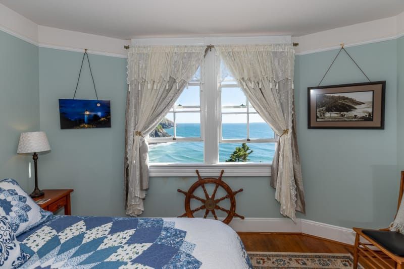 A bedroom with a bed and a window with a view of the ocean
