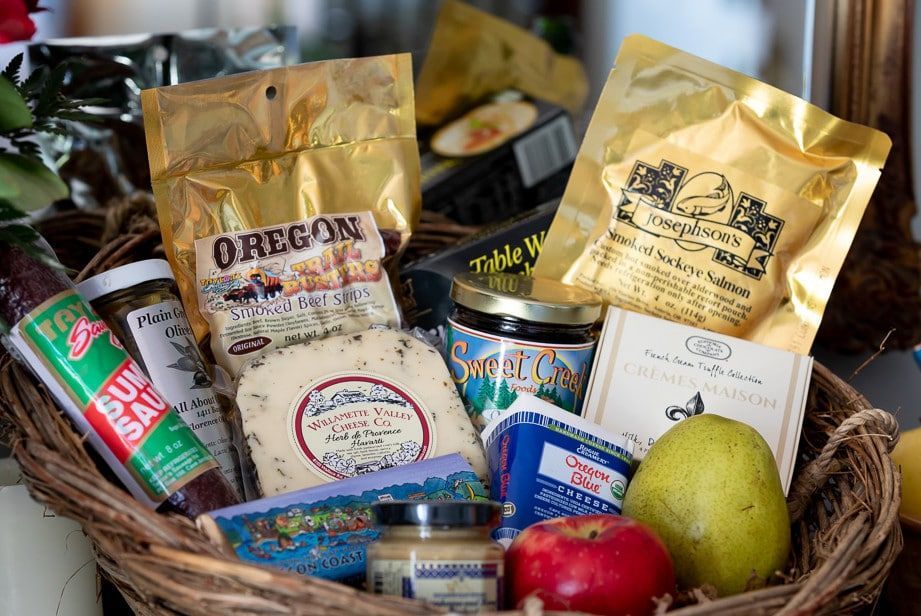 A basket filled with a variety of food including cheese and fruit