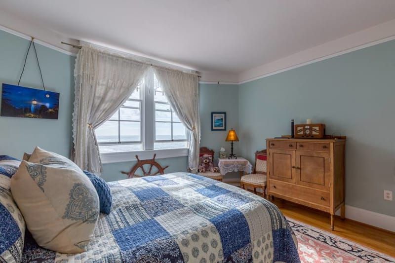 A bedroom with a bed , dresser , chair and window.