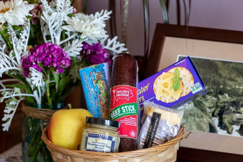 A basket filled with food and flowers is sitting on a table.