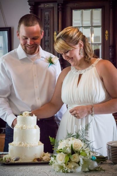 A bride and groom are cutting their wedding cake together.