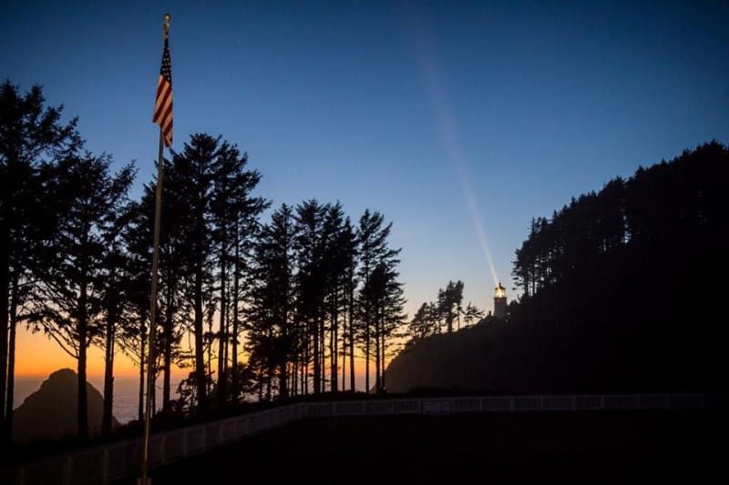 A sunset with a flag in the foreground and trees in the background