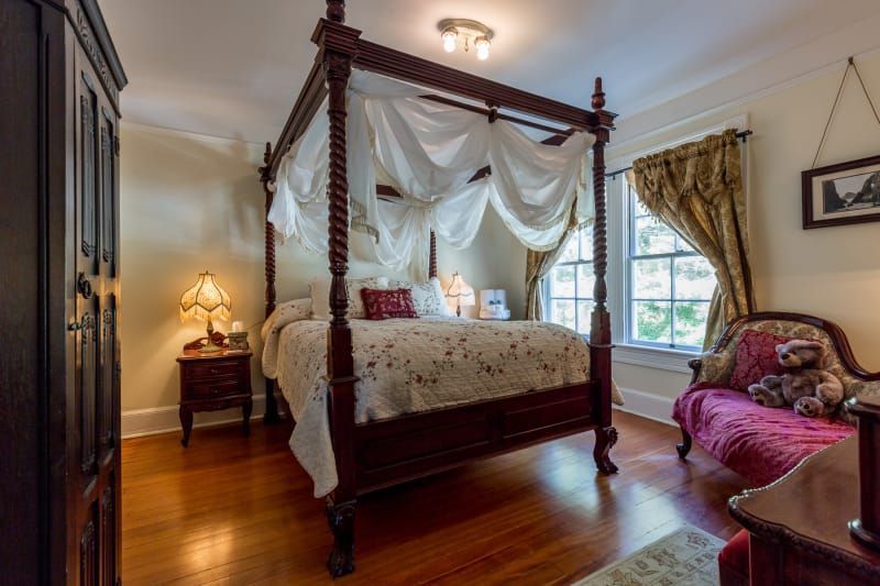 A bedroom with a canopy bed and a couch.