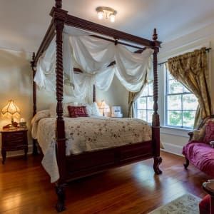 A bedroom with a canopy bed and a couch.