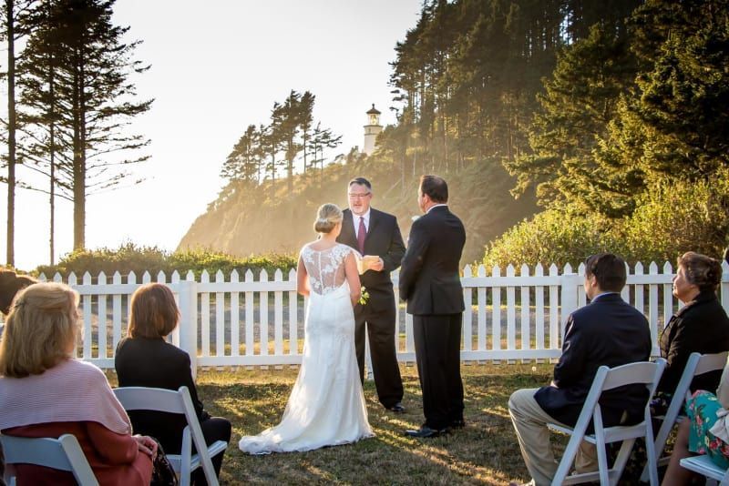 A bride and groom are getting married in front of a white picket fence.