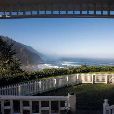 A view of the ocean from a porch with a white picket fence.
