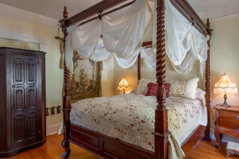A bedroom with a four poster bed and a nightstand.