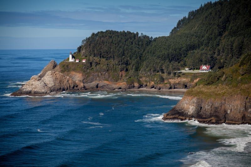 There is a lighthouse on the cliff overlooking the ocean.